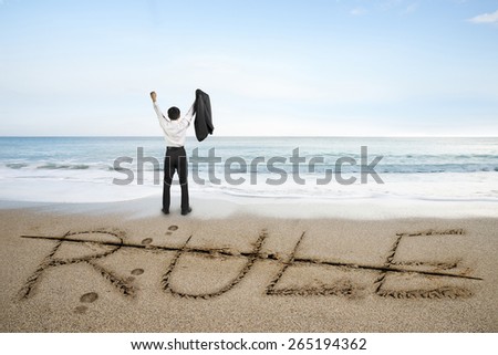 Businessman cheering with rule word deleted line written on sand beach background