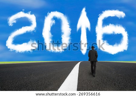 Businessman walking on asphalt road with separation white line and 2016 year arrow up sign shape clouds in the blue sky