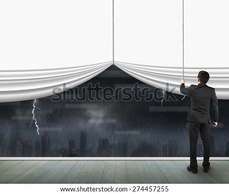 Man pulling open blank white curtain with heavy rain dark cityscape window view on wooden floor