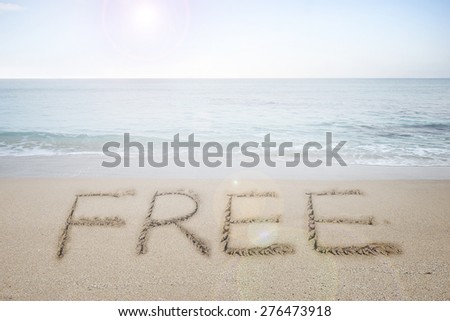 Free word handwritten in sand on sunny beach with sun sky sea background