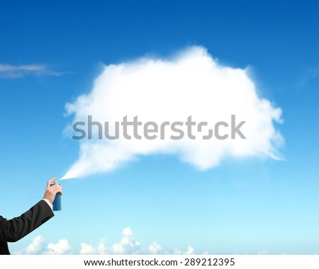 Male hand spraying white cloud paint on blue sky background