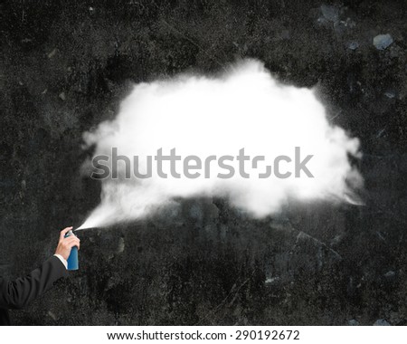 Male hand spraying white cloud paint on dark concrete wall background