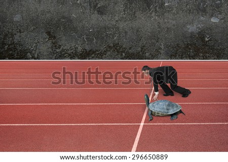Businessman and turtle are ready to race on running track, with old mottled concrete wall background. Turtle race competing metaphor concept.