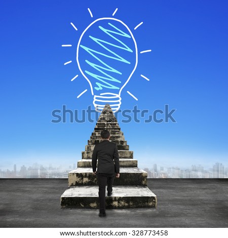 Businessman steps up old concrete stairs toward light bulb hand drawing, in blue sky background.