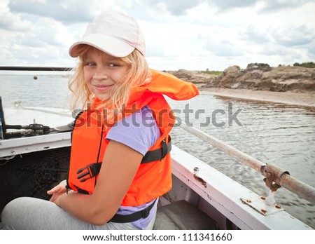 Little girl on a small boat wears bright orange life-jacket