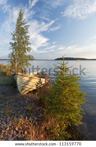Morning landscape with old row boat and trees on the coast of Saimaa lake, Finland