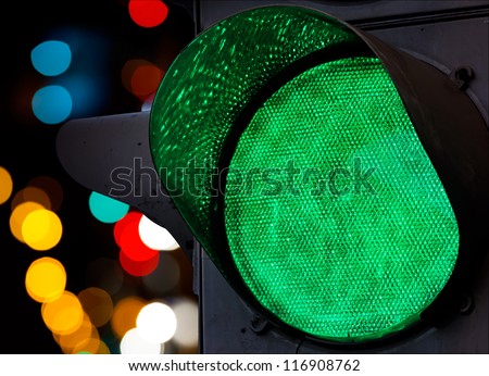 Green traffic light with colorful unfocused lights on a background