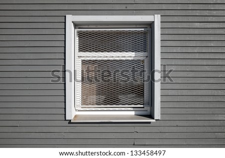 Texture of a locked window with metal grid on the gray wooden wall