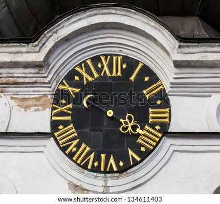 Vintage tower clock with roman numerals on white church wall in old part of Tallinn, Estonia