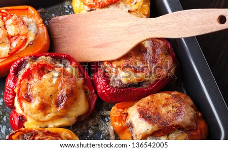 Stuffed bell peppers with chopped meat, cheese and tomato on black baking pan