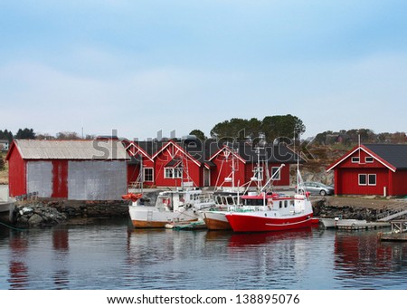 Norwegian fishing village with red wooden houses and small boats on the sea coast