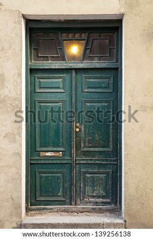 Green wooden weathered door in old building facade. Tallinn, Estonia