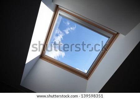 Looking up to the blue cloudy sky through modern square ceiling window