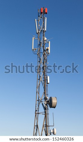 Communication radio tower with devices on blue sky background