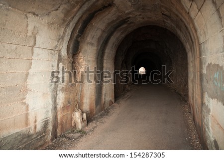 Dark abandoned tunnel interior with glowing end. Petrovac town, Montenegro