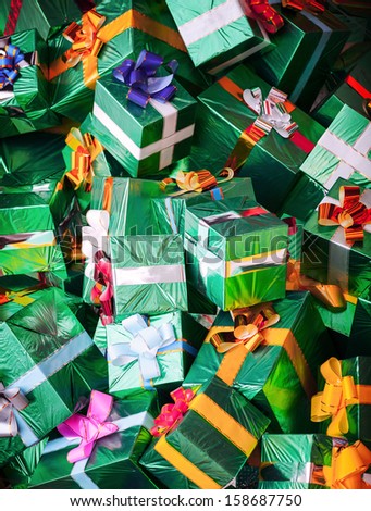 Photo background with huge pile of green shining gift boxes with colorful bows