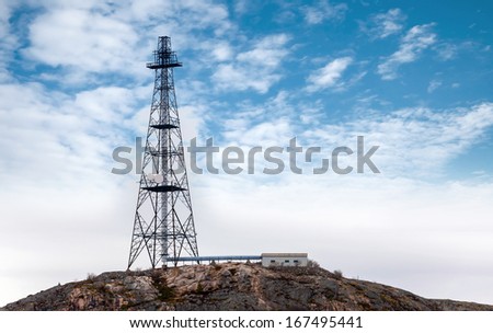 Big communication radio tower above blue cloudy sky