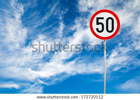 Round speed limit road sign above blue cloudy sky