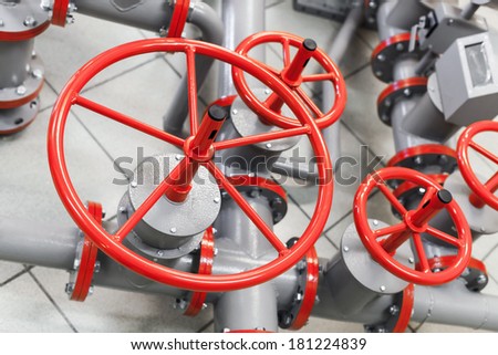 Group of red industrial valves on modern gray pipelines system