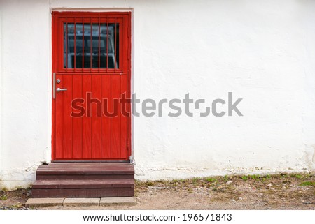 Red wooden door in white rural wall, background texture