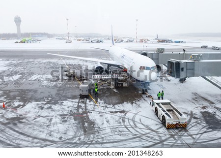SAINT-PETERSBURG, RUSSIA - MARCH 19, 2014: Snowy airport, airplane, personal and service cars
