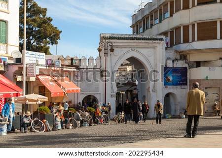 TANGIER, MOROCCO - MARCH 23, 2014: Ancient gate to Medina of Tangier, Morocco. Ordinary people walking on street