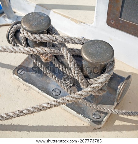 Dark bollard with rope knot on yacht deck