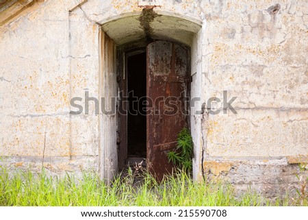 Open rusted metal door in old fortification wall, background texture