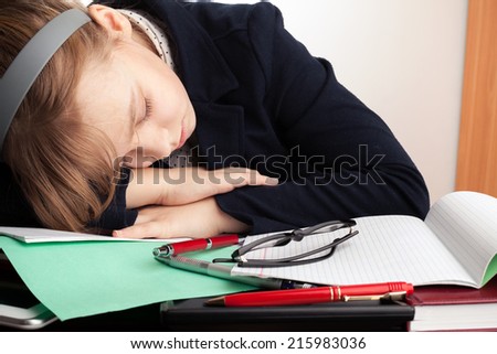 Blond Caucasian schoolgirl sleeps on the desk in school