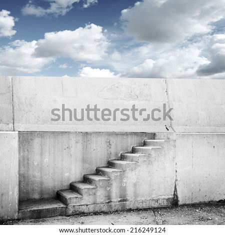Concrete wall with stairway and blue cloudy sky on background