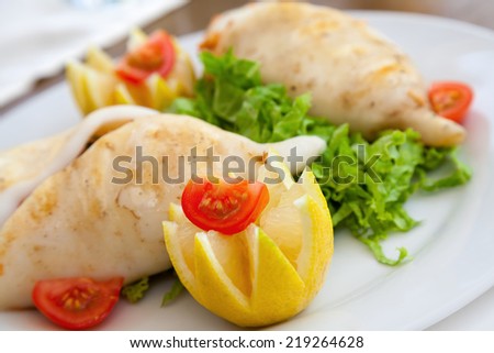Squid stuffed with seafood on white plate in restaurant