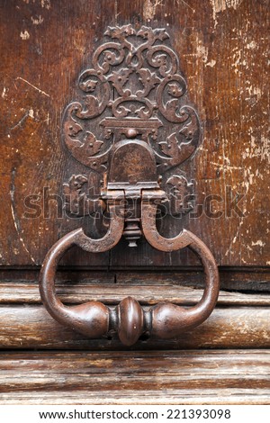 Old rusted knocker on brown wooden door in Paris, France
