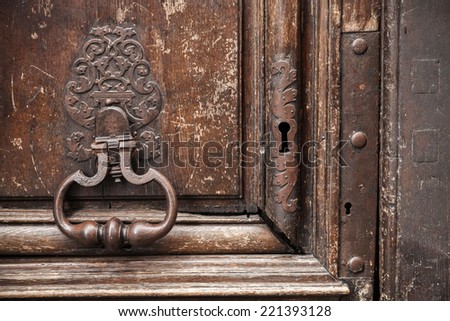 Old rusted knocker on brown wooden door. Paris, France