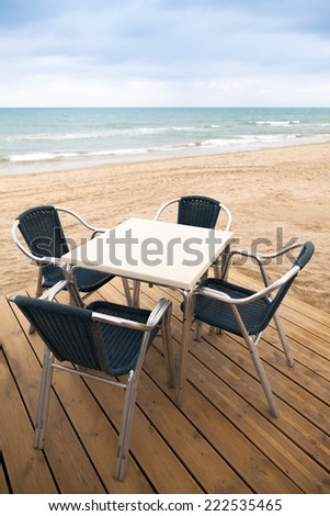 Open space sea side bar interior with wooden floor and metal armchairs on sandy beach