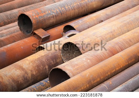 Rusted industrial steel pipes lay on the ground