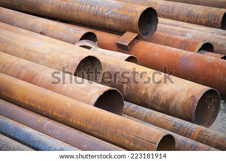 Pile of rusted industrial steel pipes lay on the ground