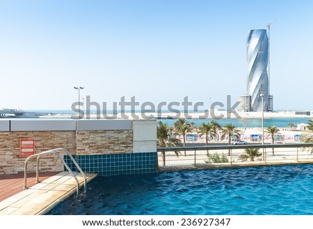 Manama, Bahrain - November 21, 2014: Swimming pool and United Tower under construction on the horizon in Manama city, Capital of Bahrain Kingdom
