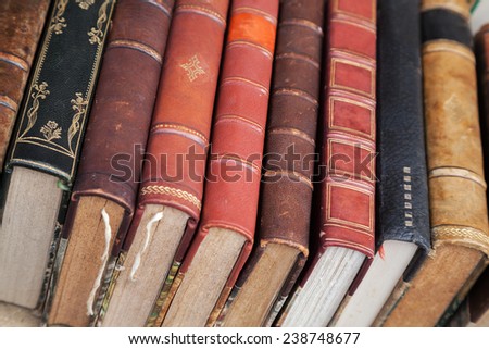 Old books with colorful leather covers lay on the market counter