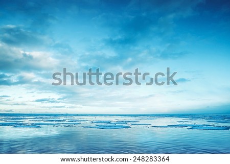 Winter coastal landscape with floating ice fragments on still sea water Gulf of Finland Russia Blue toned photo filter effect Winter coastal landscape with floating ice fragments on still sea water Gulf of Finland Russia Blue toned photo filter effect