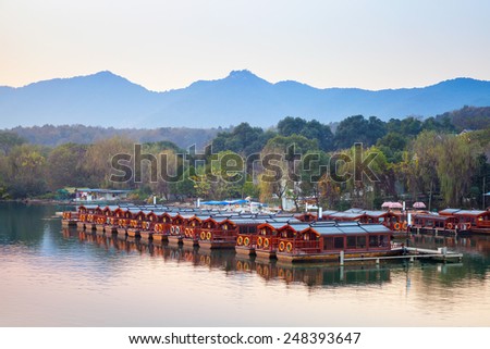 Traditional Chinese red wooden recreation boats are moored on the West Lake coast. Famous park in Hangzhou city center, China