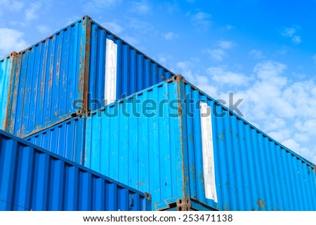 Blue metal Industrial cargo containers are stacked in the storage area under blue cloudy sky