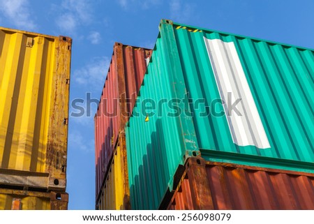 Colorful metal industrial cargo containers stacked under blue cloudy sky