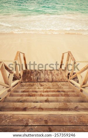 Empty wooden stairs goes down to the sea. Retro toned photo with vintage filter effect