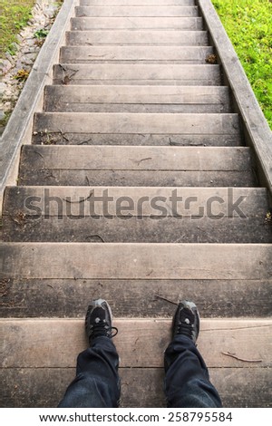 Male legs stand on old wooden stairs, looking down
