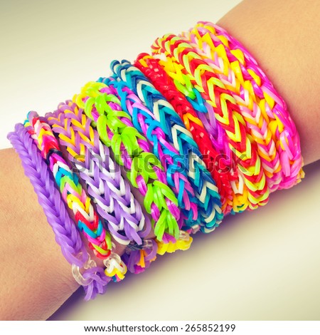 Colorful rubber rainbow loom band bracelets on wrist, trendy kids fashion accessories.  Vintage retro tonal photo filter correction, instagram style