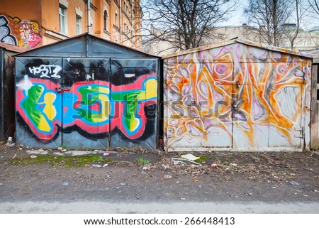 Saint-Petersburg, Russia - April 3, 2015: Two old rusted locked garages with colorful grungy graffiti. Vasilievsky island, Central old part of St. Petersburg city