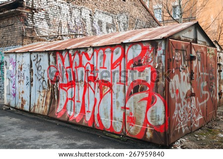 Saint-Petersburg, Russia - April 3, 2015: Old rusted locked abandoned garage with colorful chaotic grungy graffiti. Vasilievsky island, Central old part of St. Petersburg city