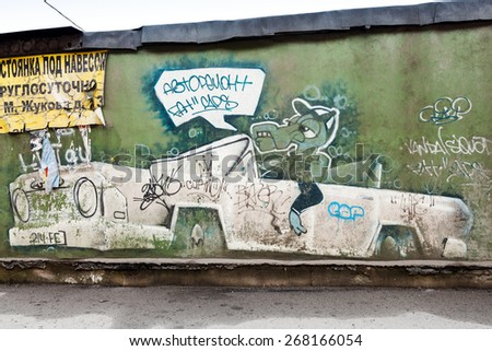 Saint-Petersburg, Russia - April 6, 2015: Graffiti with crocodile in the car on old green concrete wall. Advertisement text in Russian means: roofed parking around the clock, car repair