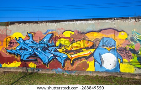 Saint-Petersburg, Russia - April 6, 2015: Colorful graffiti with chaotic text elements and blue angry penguin bird over old gray concrete garage walls