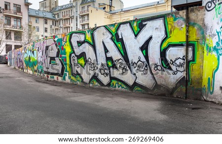 Saint-Petersburg, Russia - April 7, 2015: Colorful chaotic graffiti text patterns over old gray concrete fence